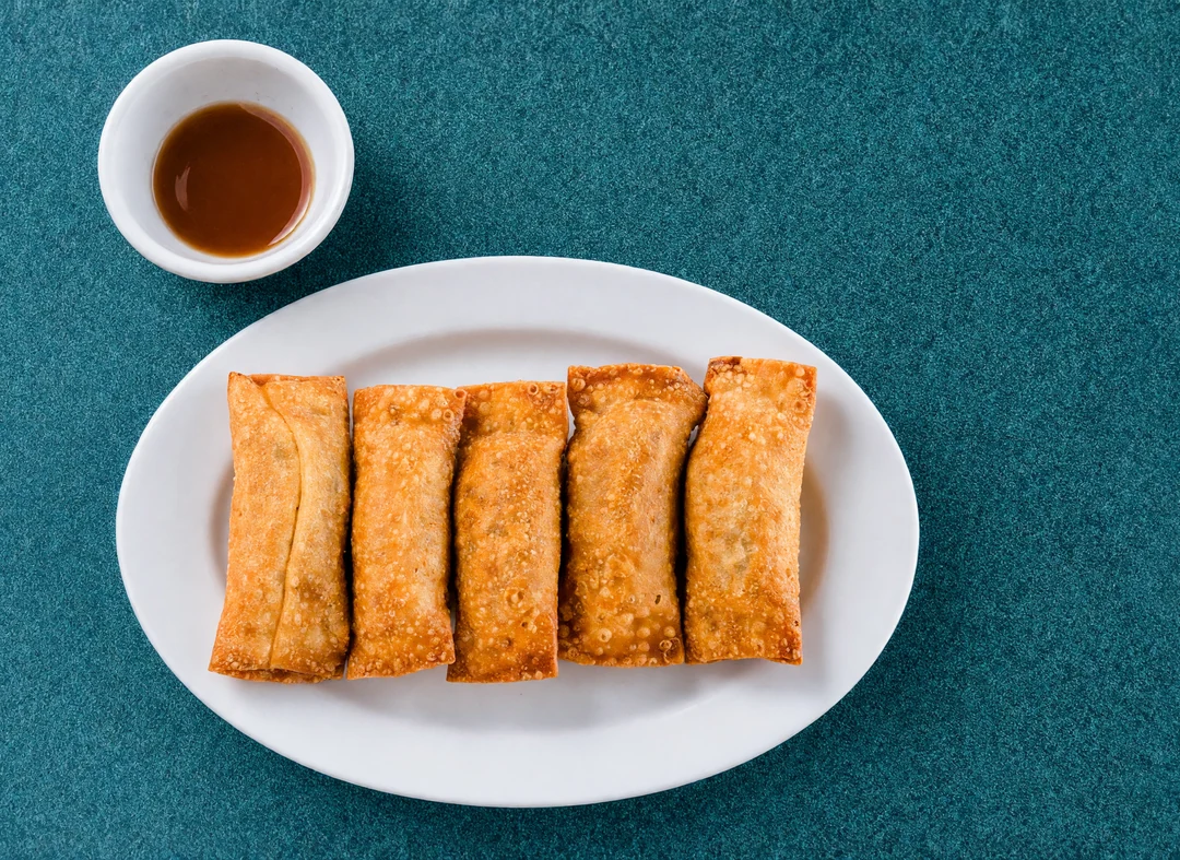 Five egg rolls with a cup of plum sauce